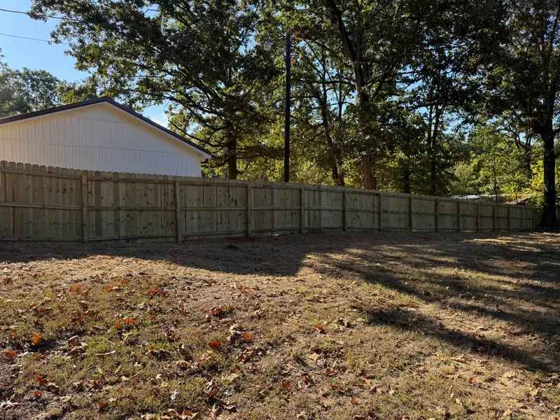 Long run of new wood privacy fence in a wooded yard