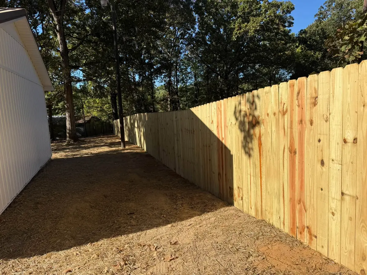 New wood privacy fence running along the side of a metal building